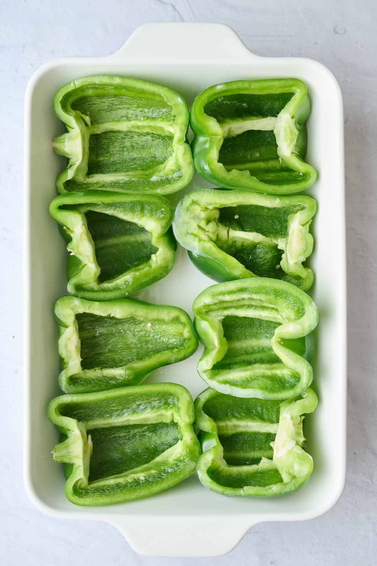 Pepper halves added to a baking dish.
