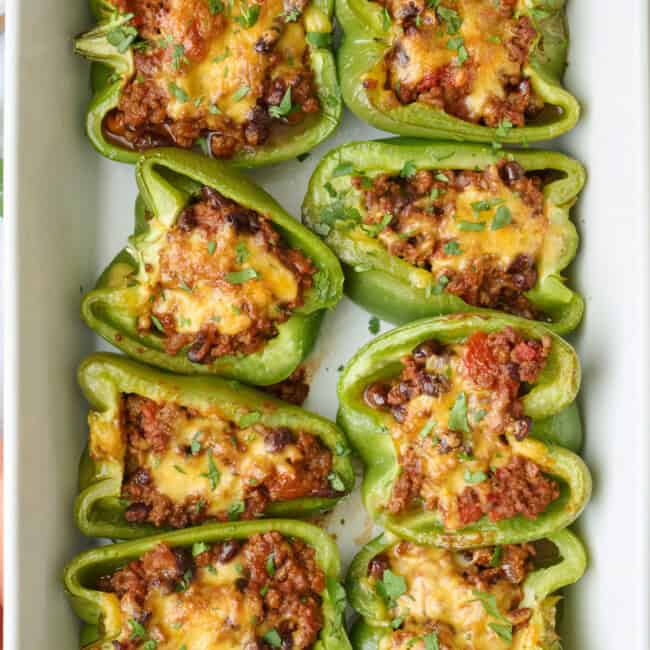 Taco stuffed bell peppers in the baking dish garnished with chopped cilantro,