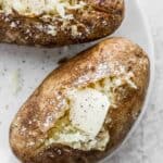 Two baked potatoes with butter on top