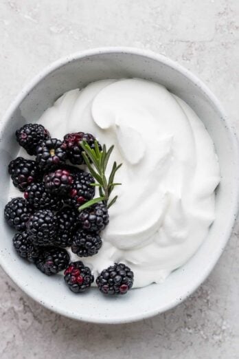 Homemade whipped cream with blackberries and rosemary
