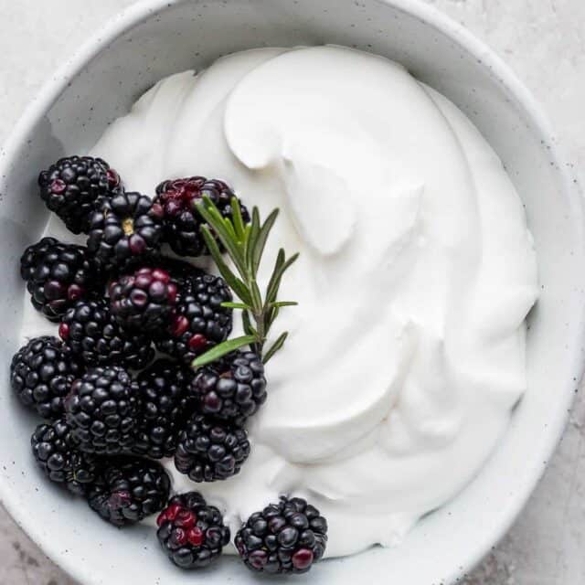 Homemade whipped cream with blackberries and rosemary