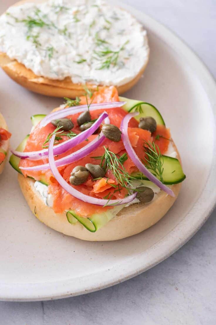 Smoked salmon bagel sandwich topped with cucumbers, capers and onions