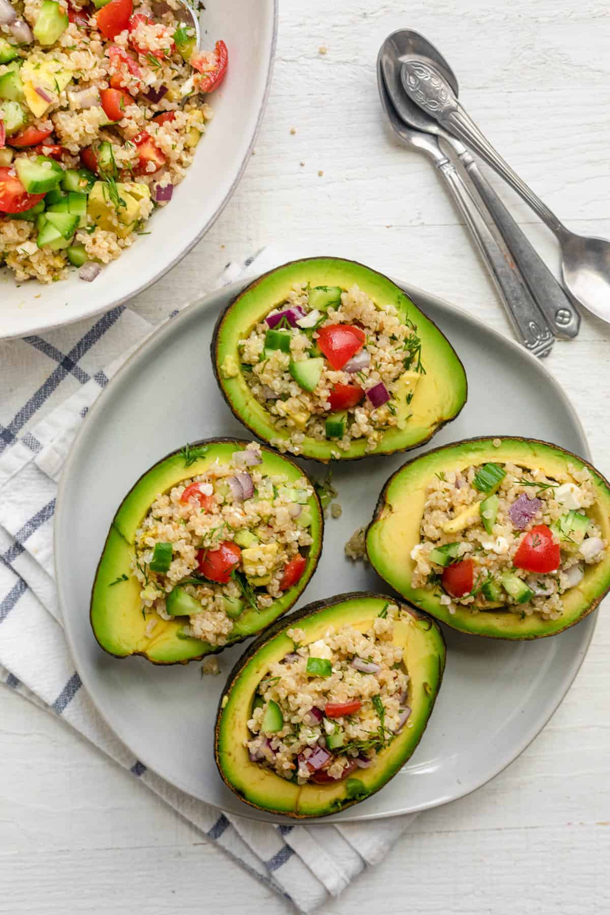 Avocado stuffed quinoa salad with small spoons next to them