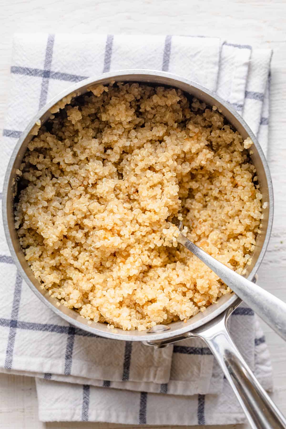 Cooked quinoa in pot with fork to fluff it