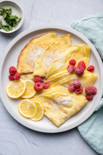 Crepes with lemon and sugar served with raspberries