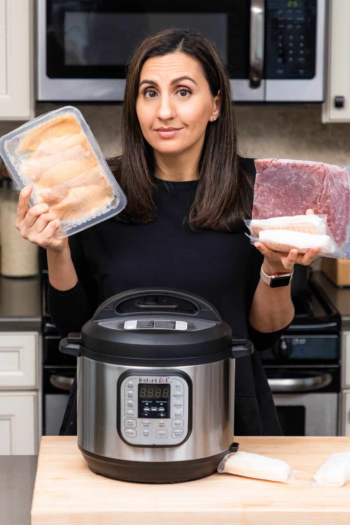 Yumna holding frozen chicken, beef and fish with instant pot