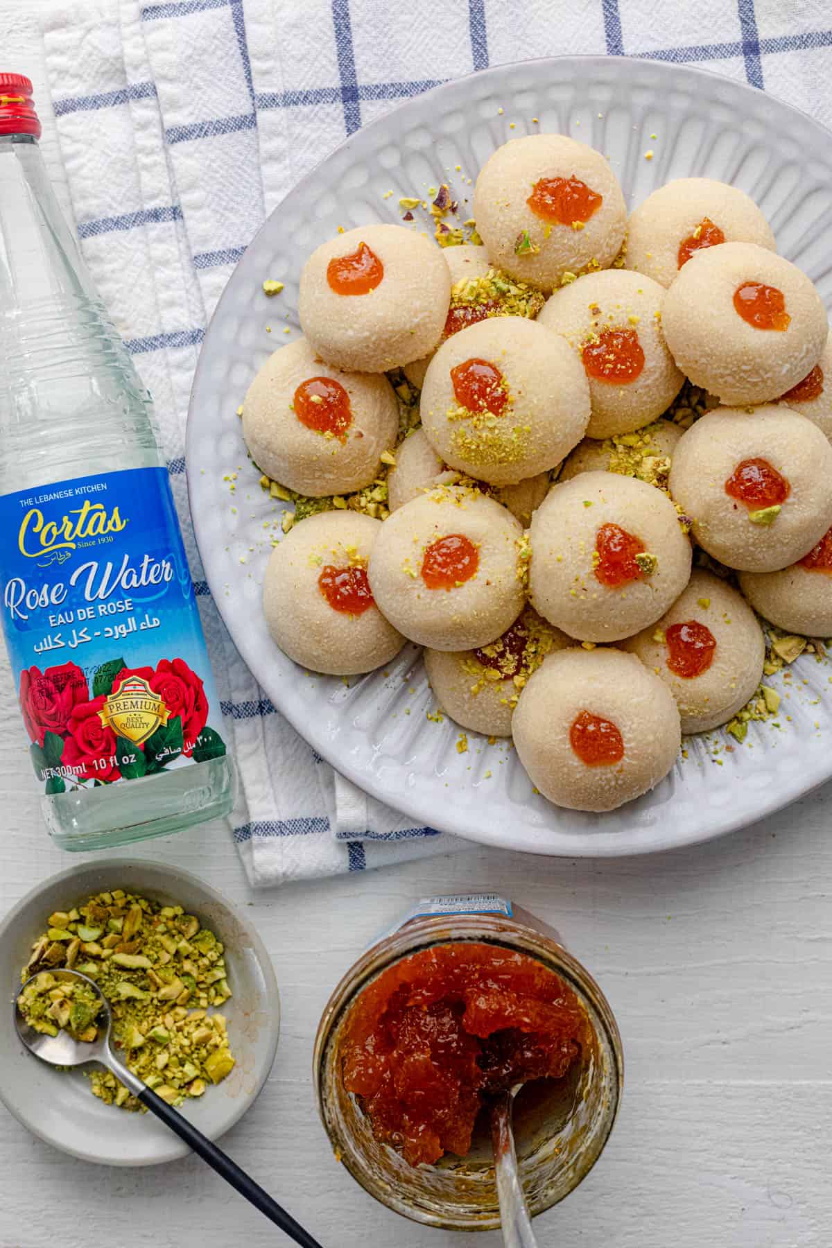 Ghraybeh cookies on a plate with bottle of Cortas rose water and Apricot Jam from Cortas