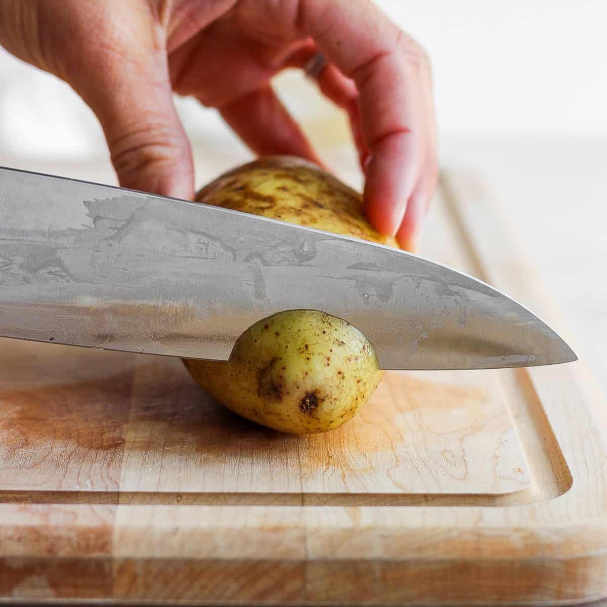 Cutting the root of the potato off.