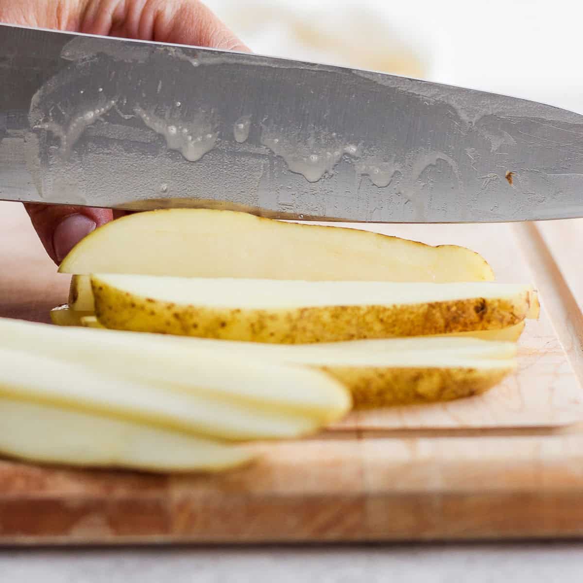 Stacked slices together, cut side down, cutting lengthwise.