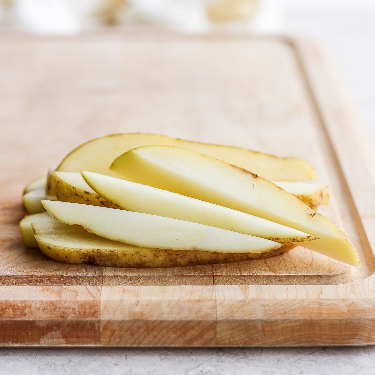 Potato sticks on cutting board after cut.