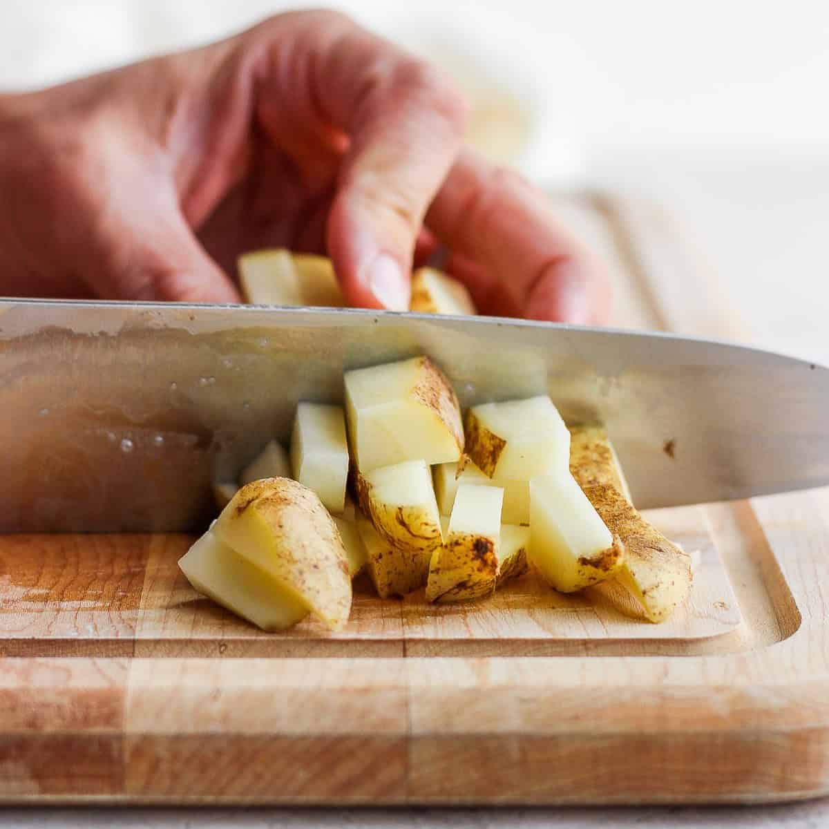 Potato sticks bunched together, cutting small sections perpendicularly.