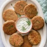 Lentil cakes on serving dish with yogurt dill sauce in the middle