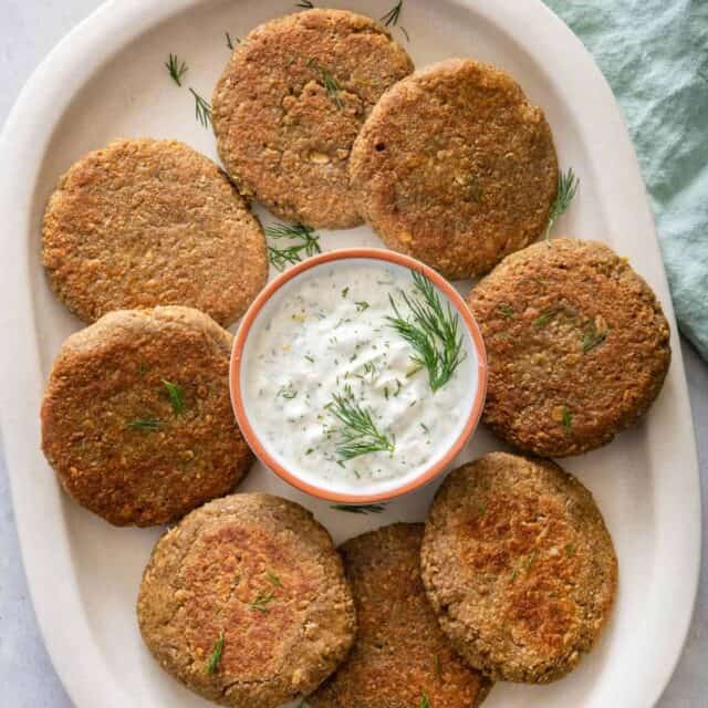 Lentil cakes on serving dish with yogurt dill sauce in the middle