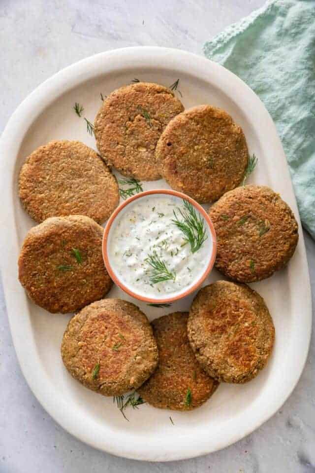 Lentil cakes on serving dish with yogurt dill sauce in the middle