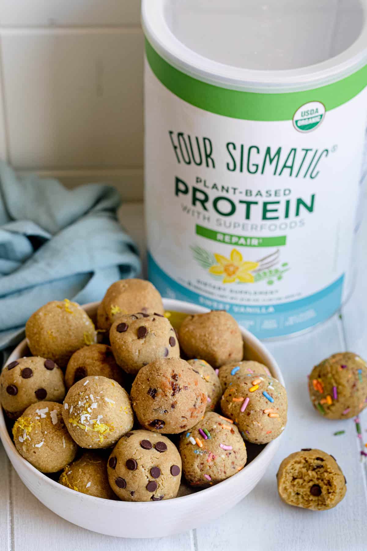 Bowl of different flavors of protein balls with Four Sigmatic protein powder in background