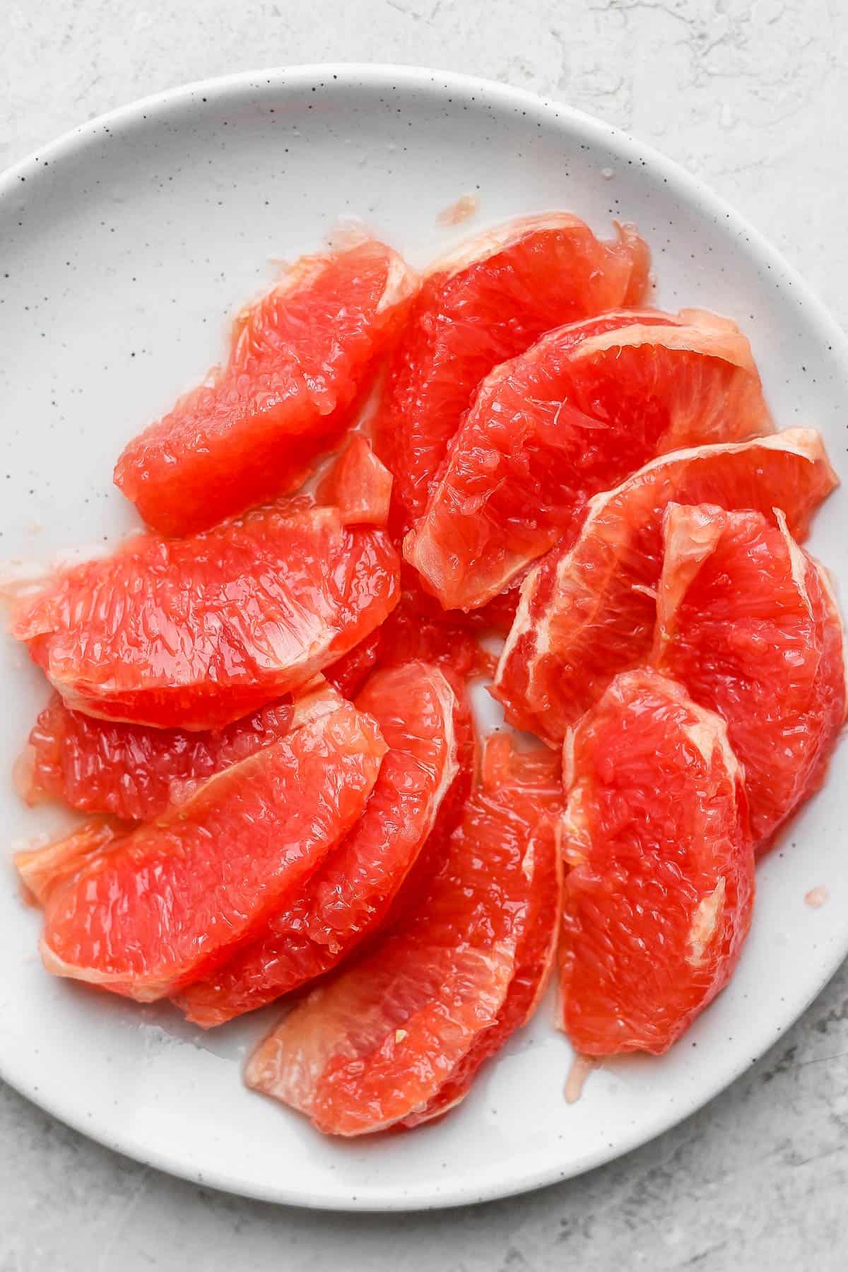 Segmented grapefruit on a white plate