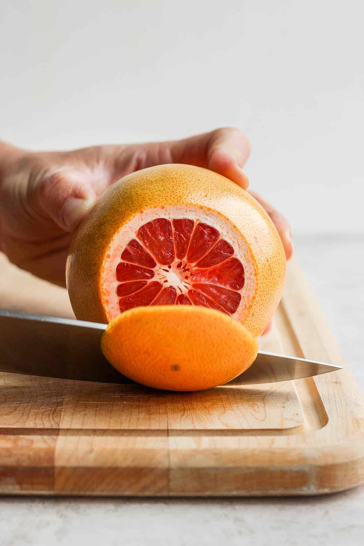 Slicing off top of grapefruit on cutting board