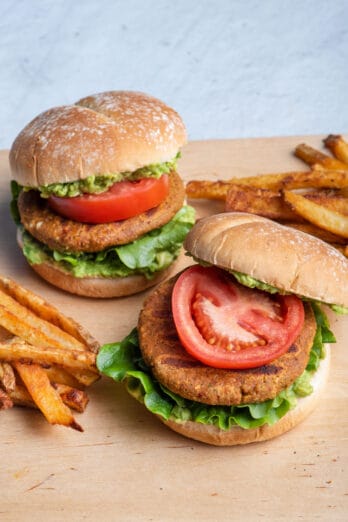 2 chickpea burgers on a cutting board with fries next to them