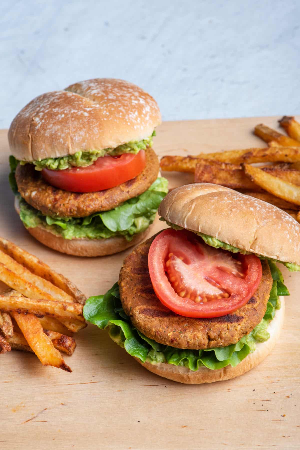 2 chickpea burgers on a cutting board with fries next to them