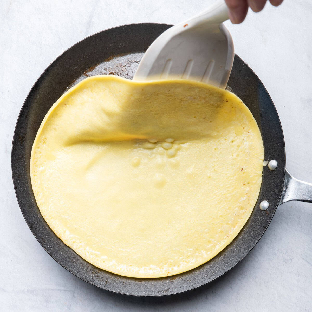 Sliding spatula under edges to flip.