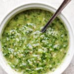 Close up shot of the chimichurri sauce in a small bowl with a spoon