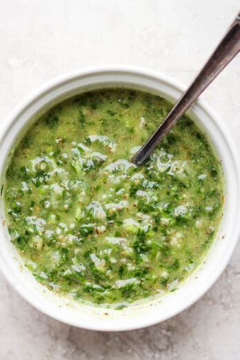 Close up shot of the chimichurri sauce in a small bowl with a spoon