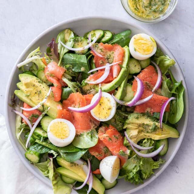 Smoked salmon salad in a large plate with dressing on the side
