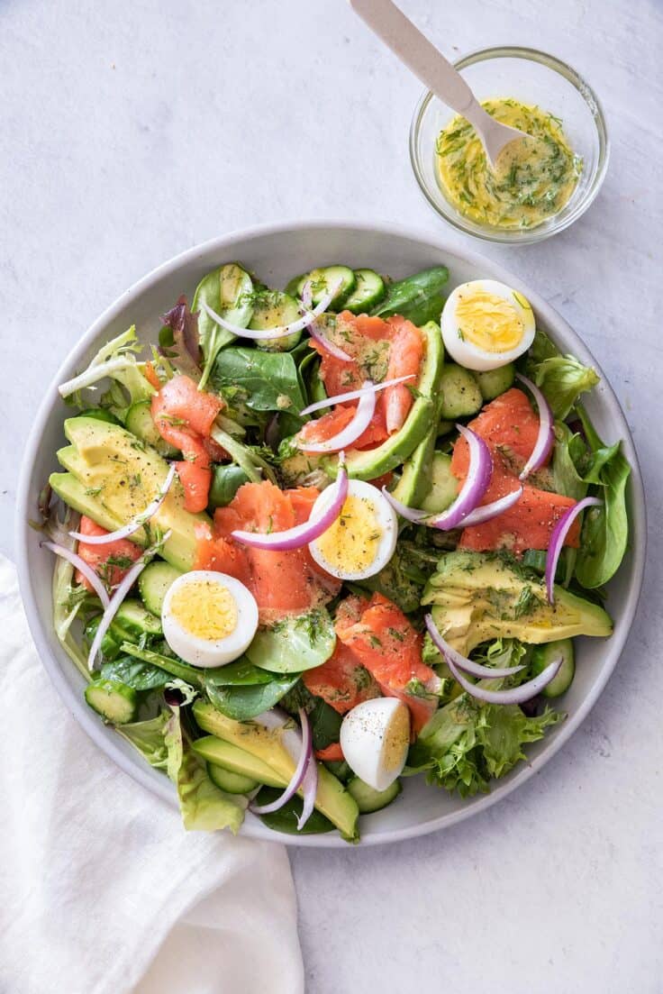 Smoked salmon salad in a large plate with dressing on the side
