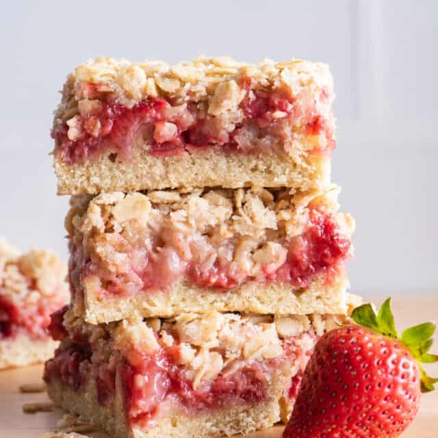 3 strawberry oat bars stacked on top of each other with large strawberry in front