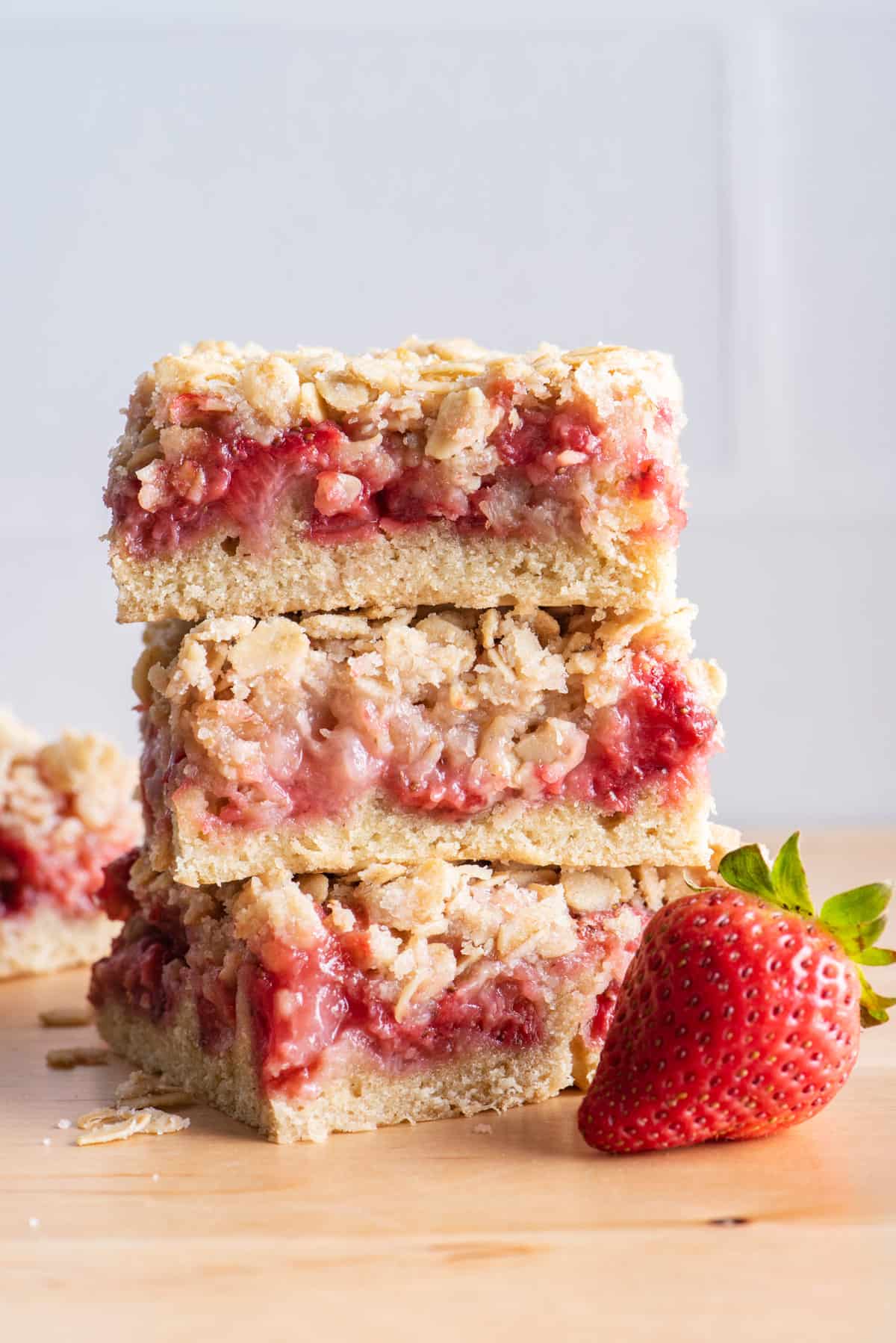 3 strawberry oat bars stacked on top of each other with large strawberry in front