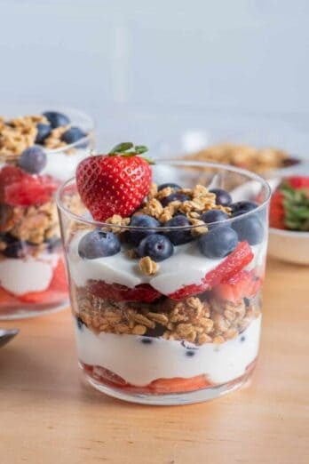 Cup of layered yogurt and fruit parfait with red, white and blue layers including strawberries and blueberries