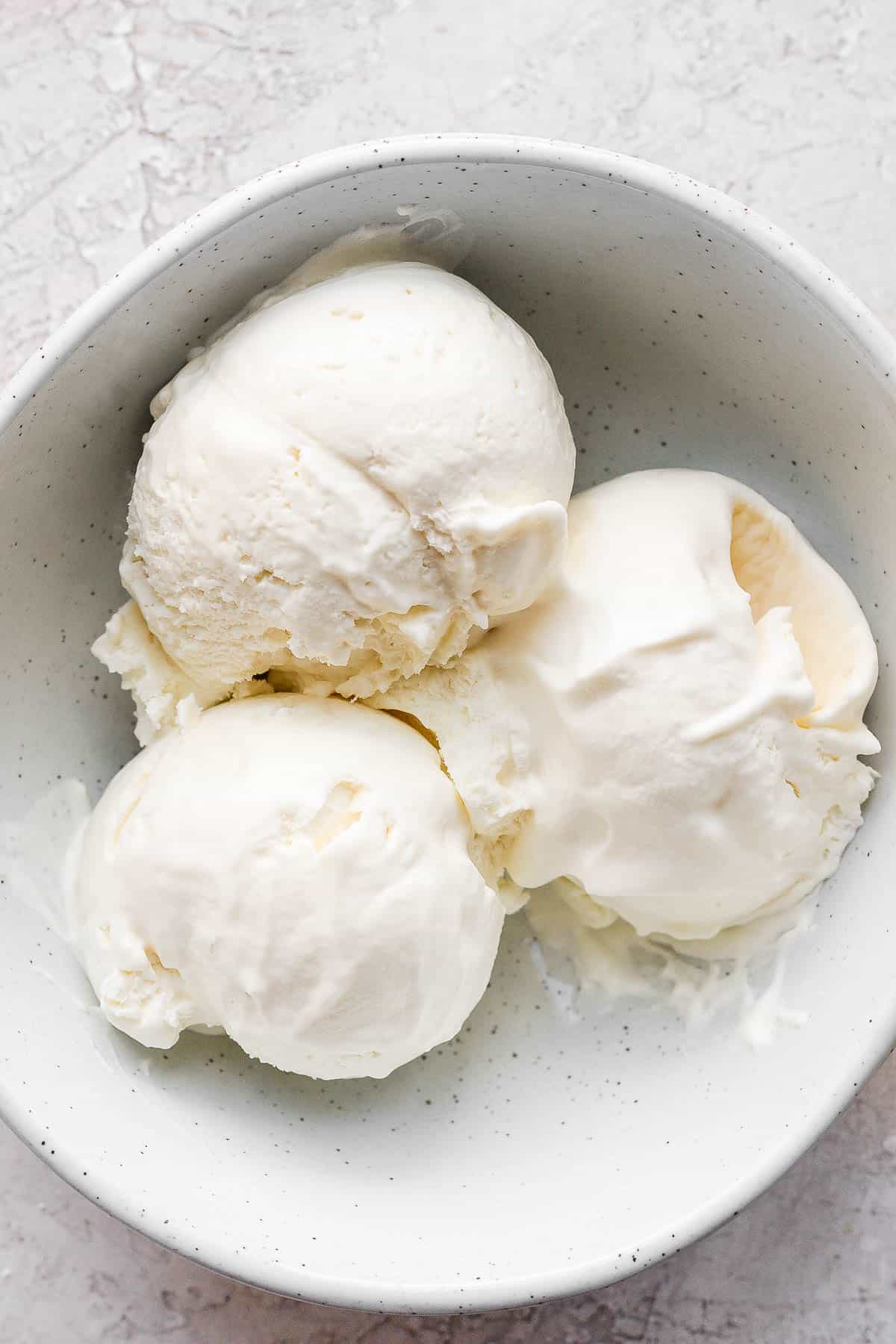 3 scoops of homemade vanilla ice cream in a small white bowl