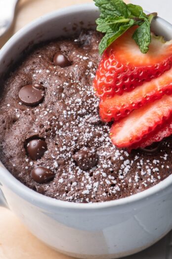 A chocolate mug cake with strawberries on top.