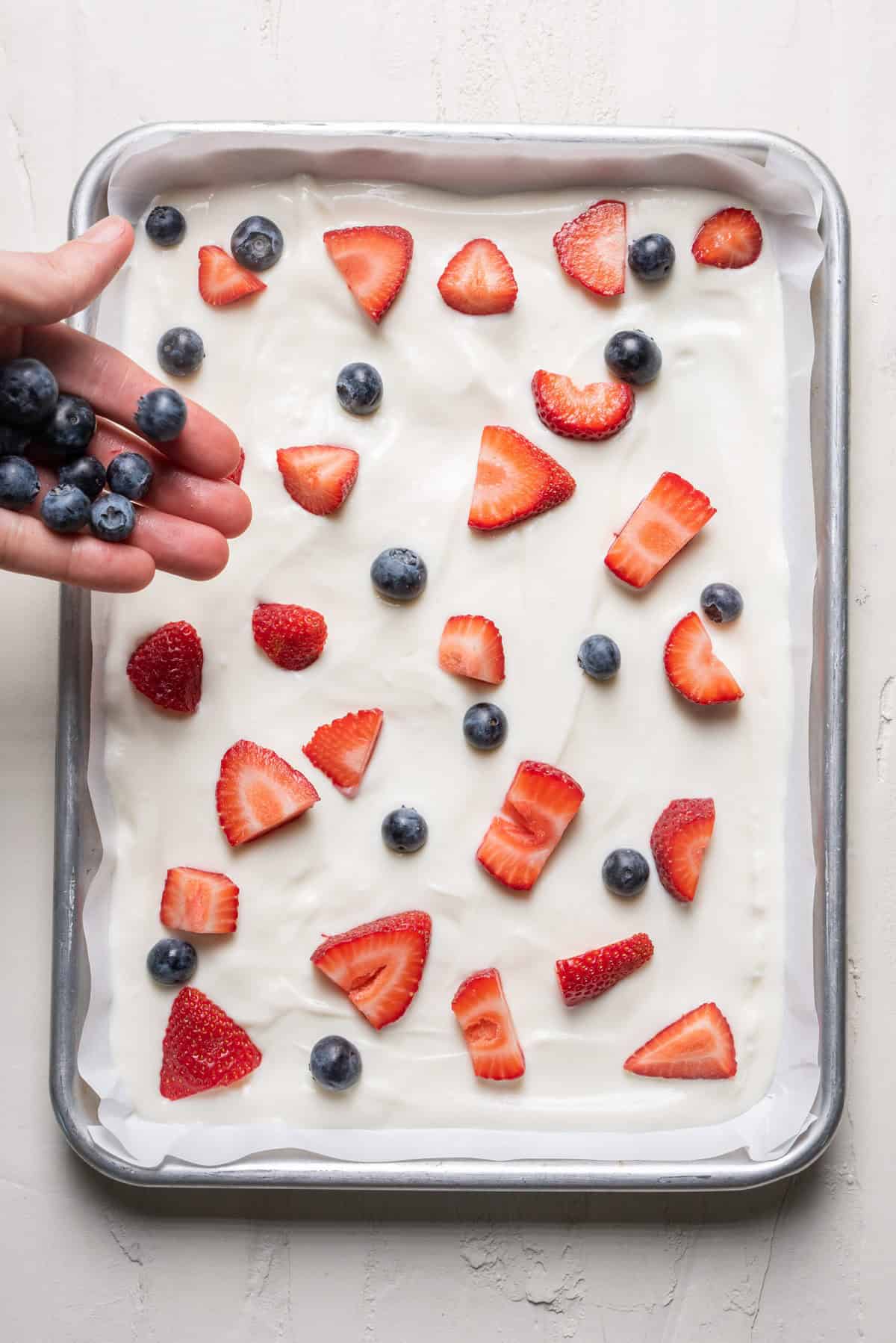 Sprinkling blueberries on top of the yogurt.