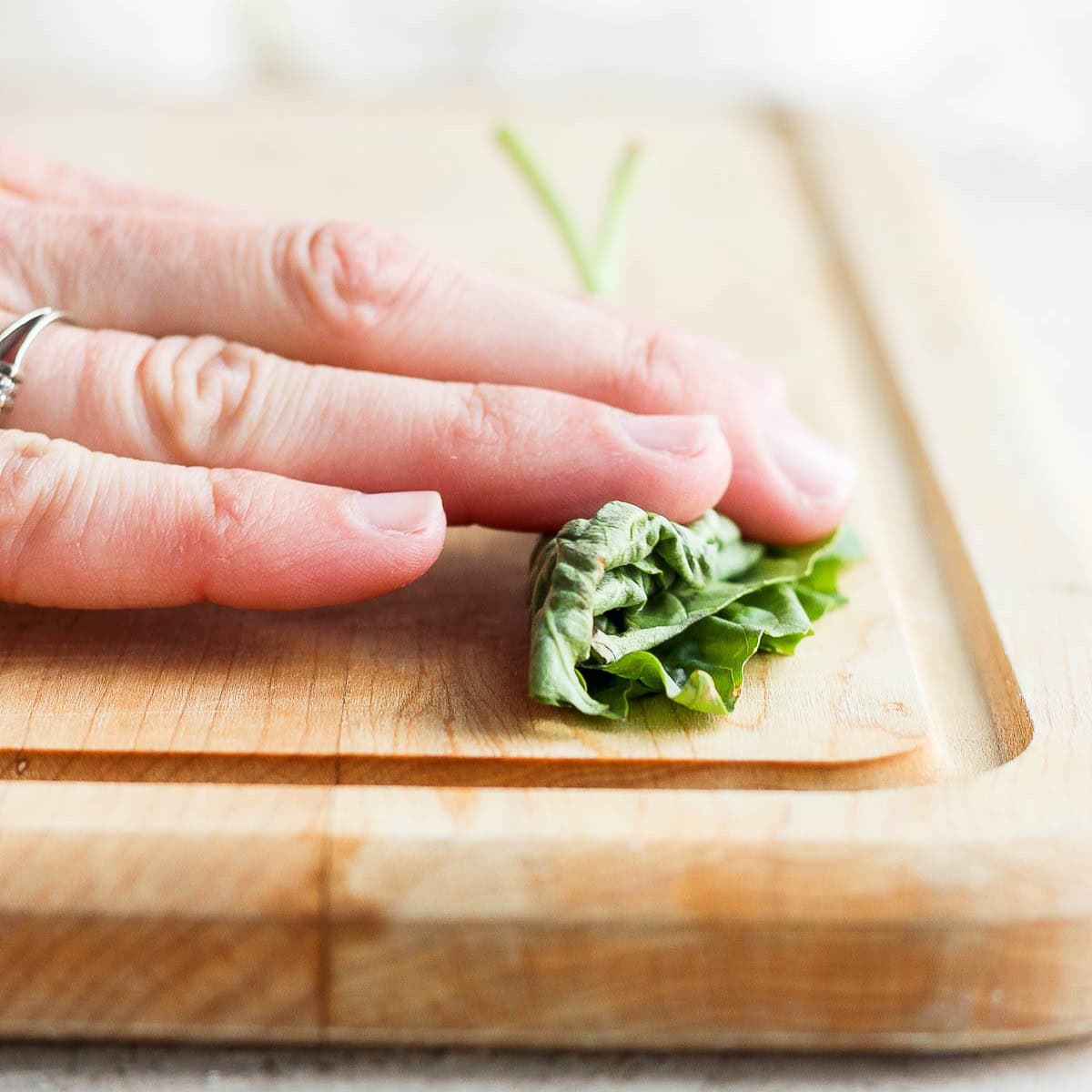 Fingers rolling the basil.