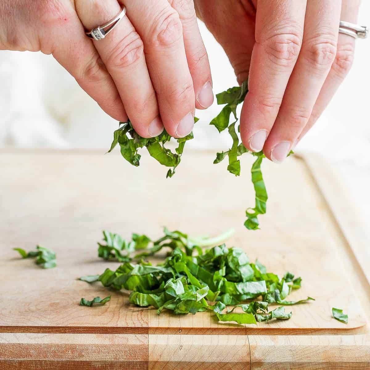 Fingers separating the basil ribbons.