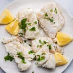 Cooked fish on plate with lemon wedges