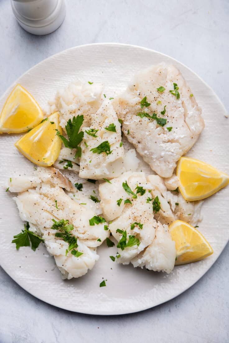 Cooked fish on plate with lemon wedges