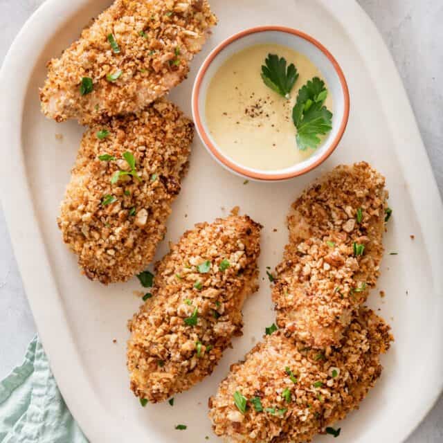 Pecan crusted chicken on a plate with honey mustard dipping sauce
