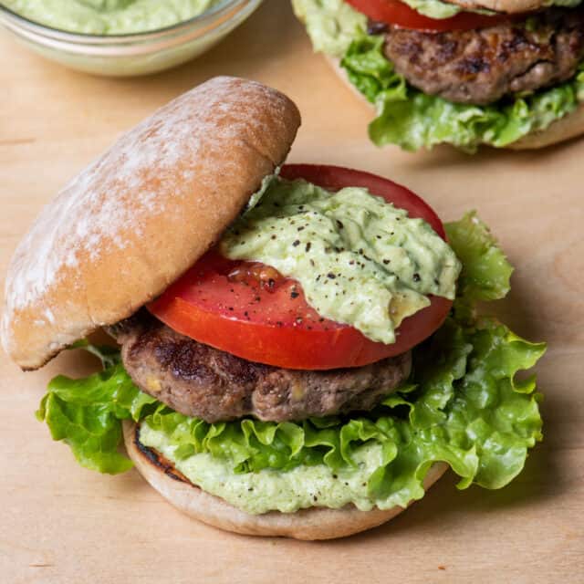 Two avocado burgers with avocado crema on the side