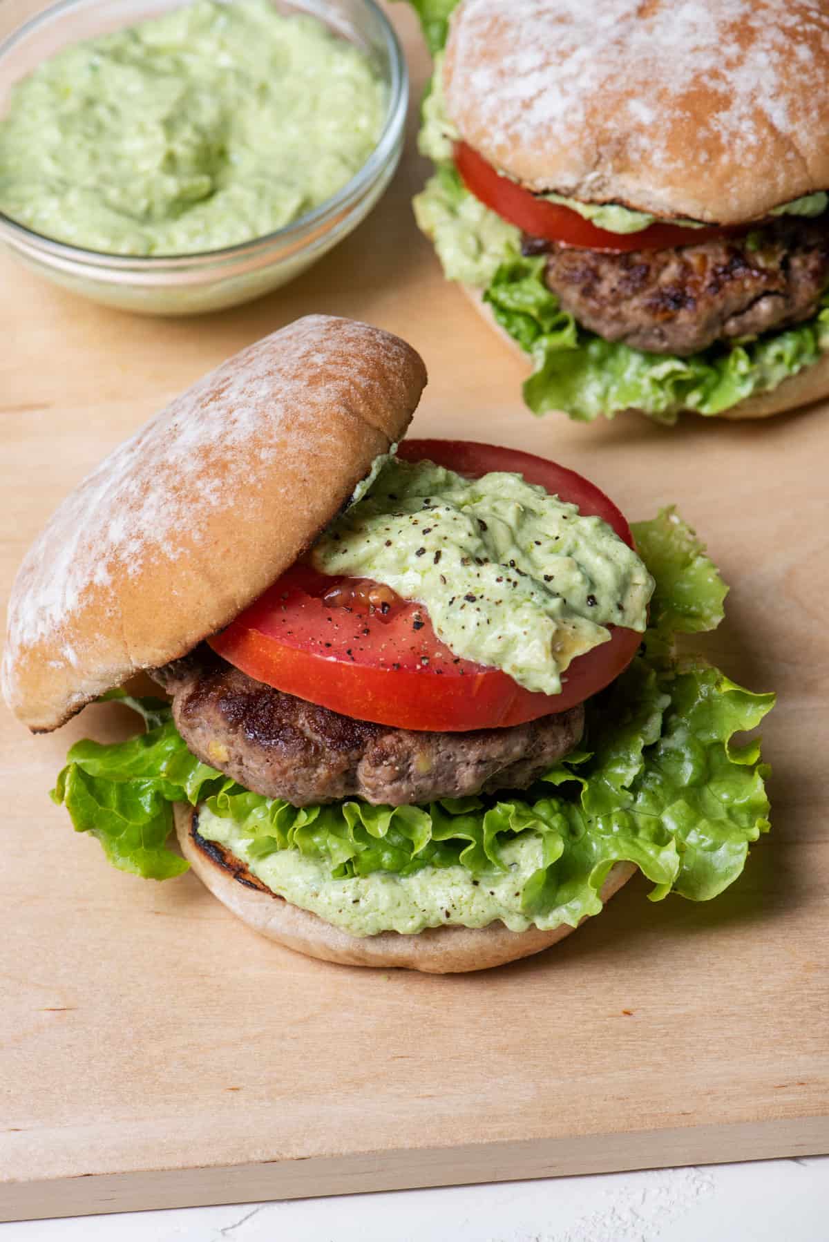 Two avocado burgers with avocado crema on the side