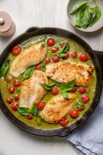 Creamy pesto chicken in a skillet with cherry tomatoes