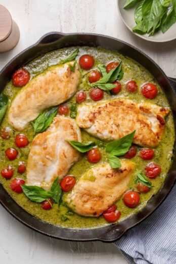 Creamy pesto chicken in a skillet with cherry tomatoes