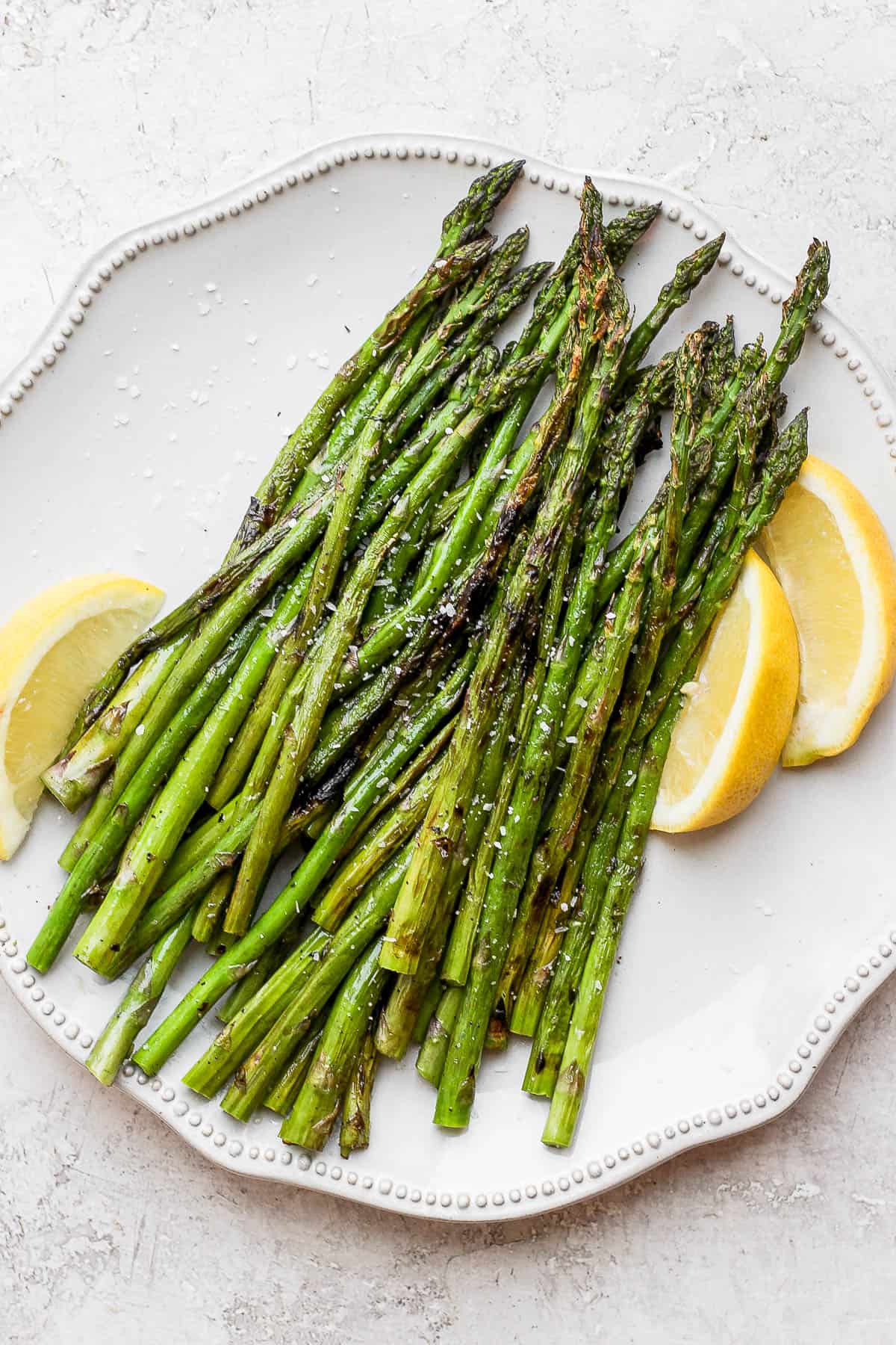 Plate of grilled asparagus with lemon wedges