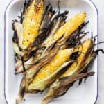 Pan of grilled corn with husks