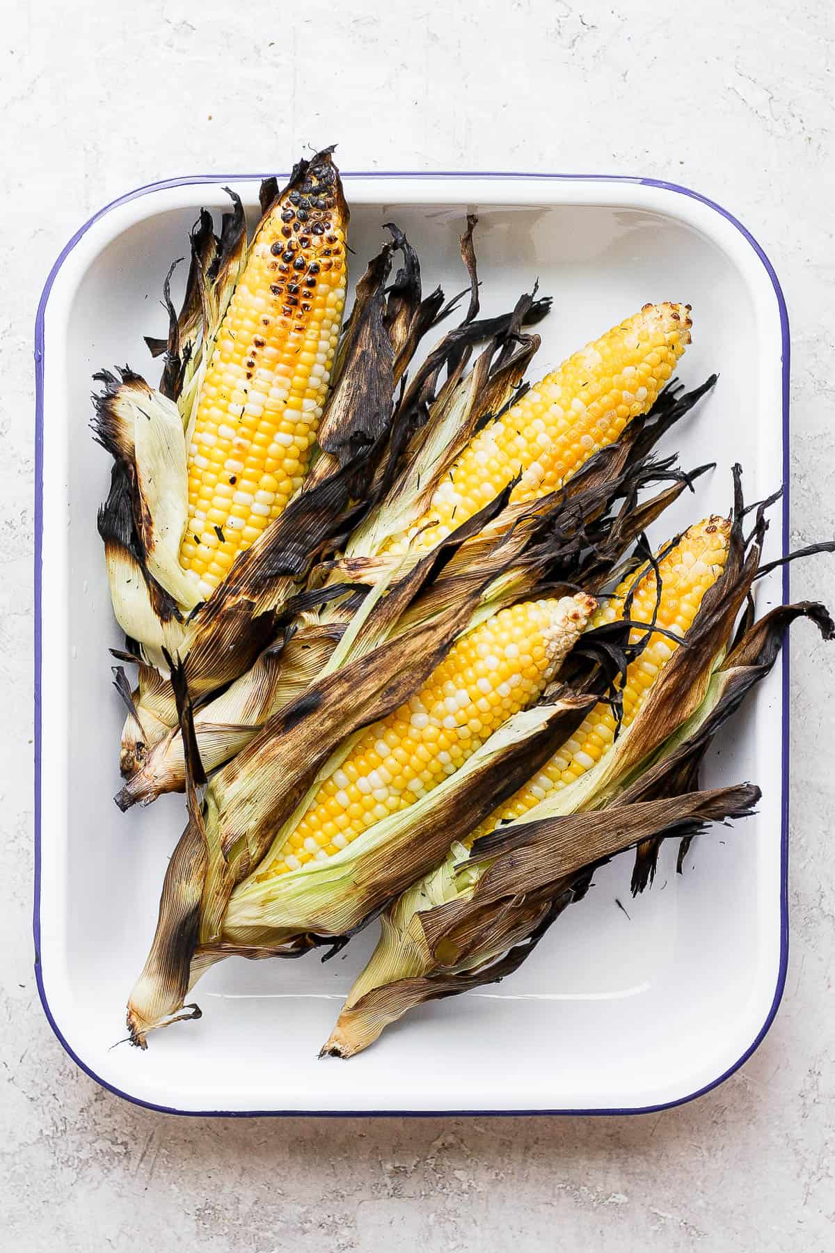 Pan of grilled corn with husks