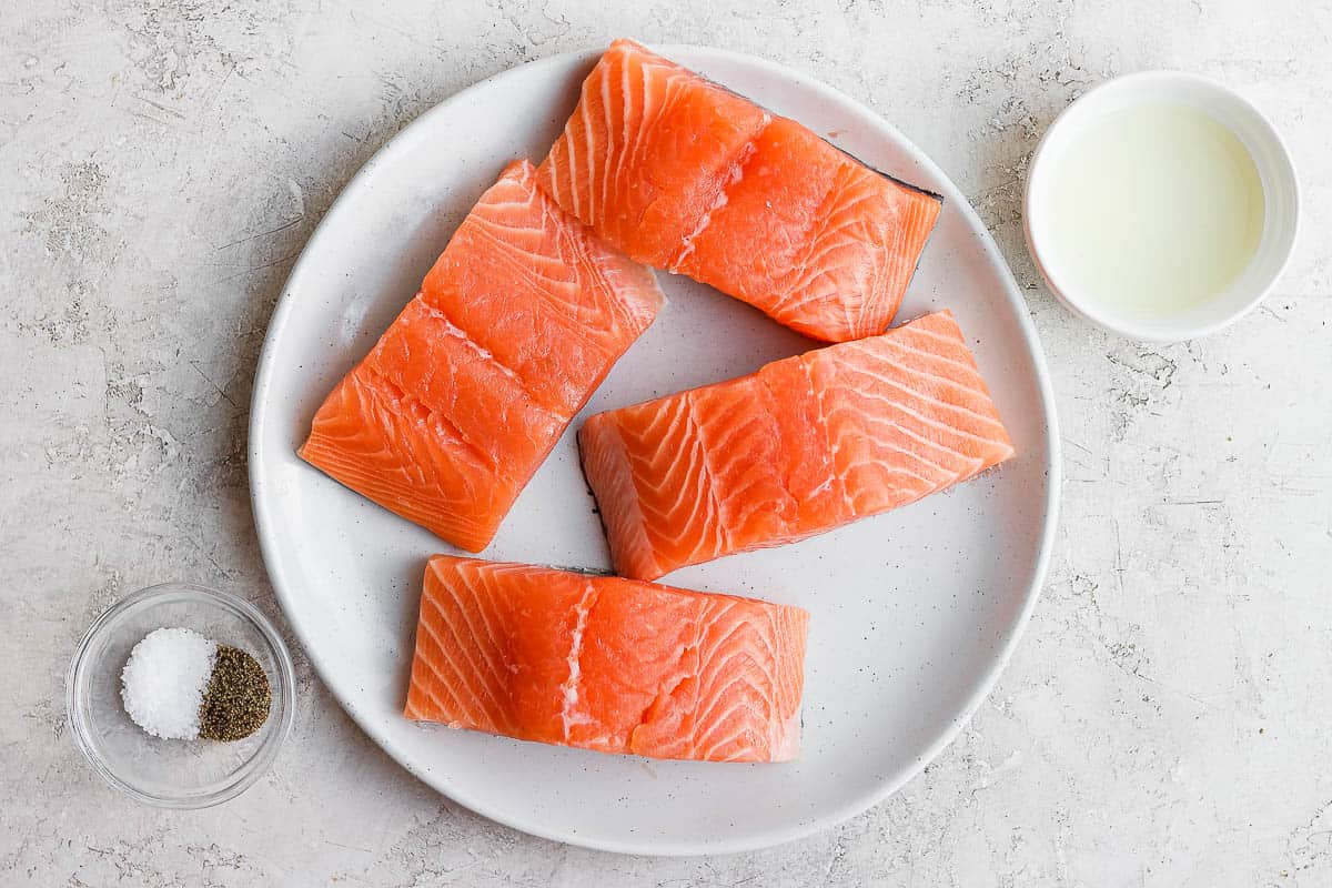 4 salmon fillets on plate with oil, salt and pepper