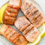 Plate of 4 salmon fillets grilled served with lemon wedges
