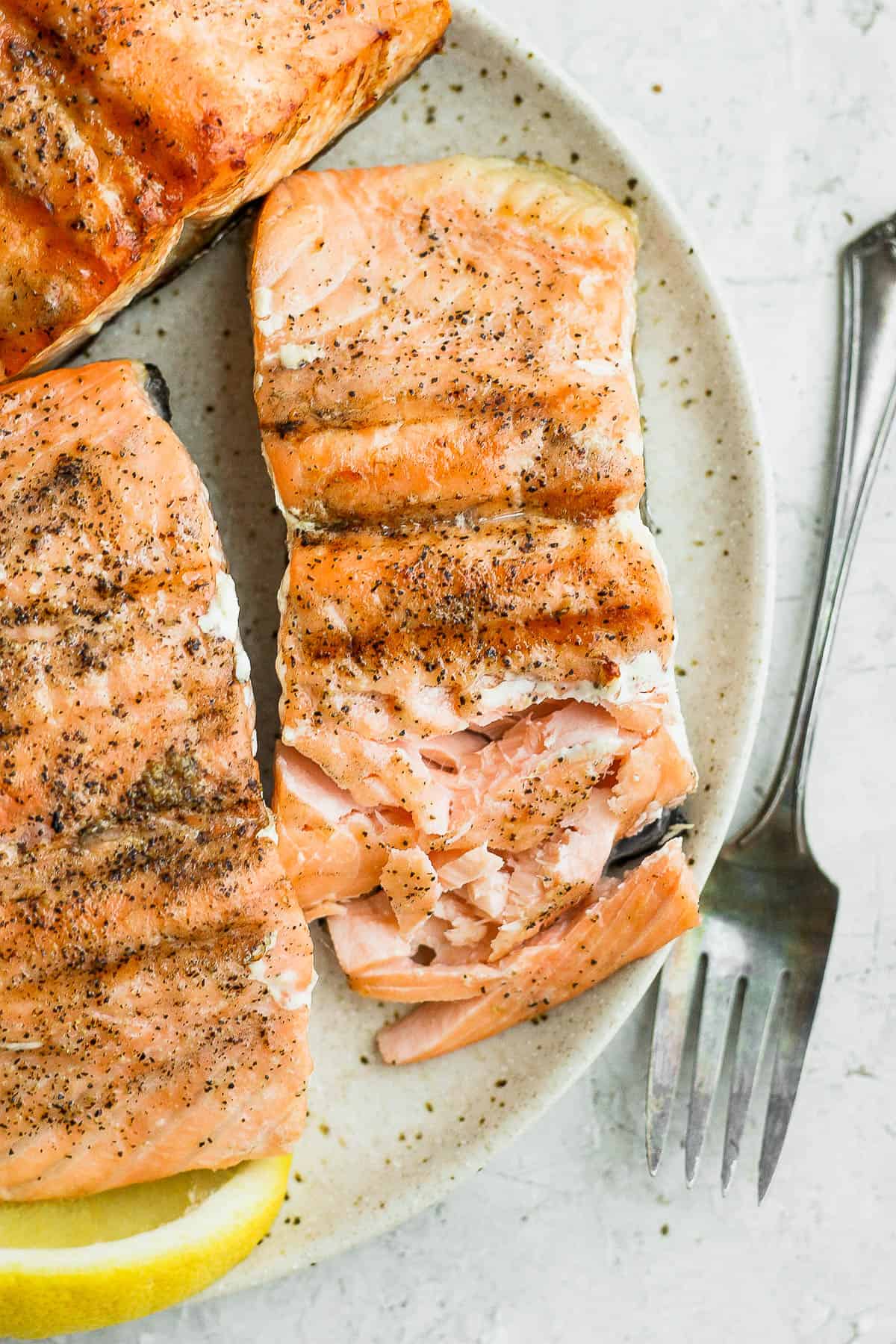 Grilled salmon fillets on plate with fork next to plate