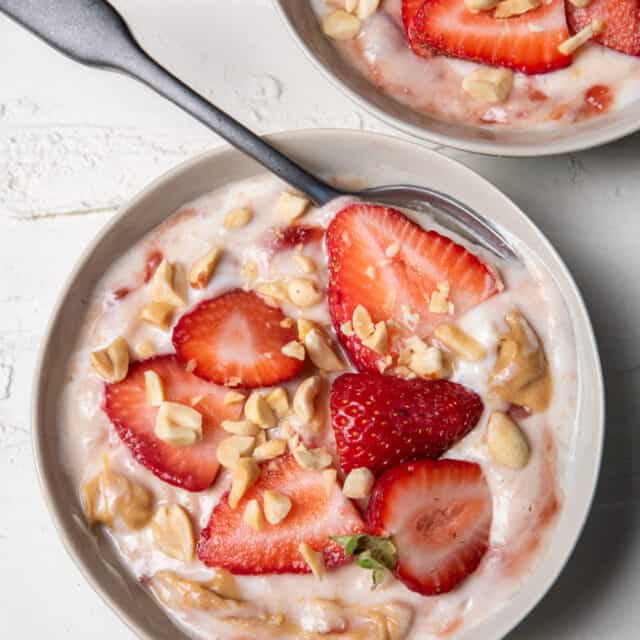Peanut butter jelly yogurt in a bowl topped with strawberries and peanuts